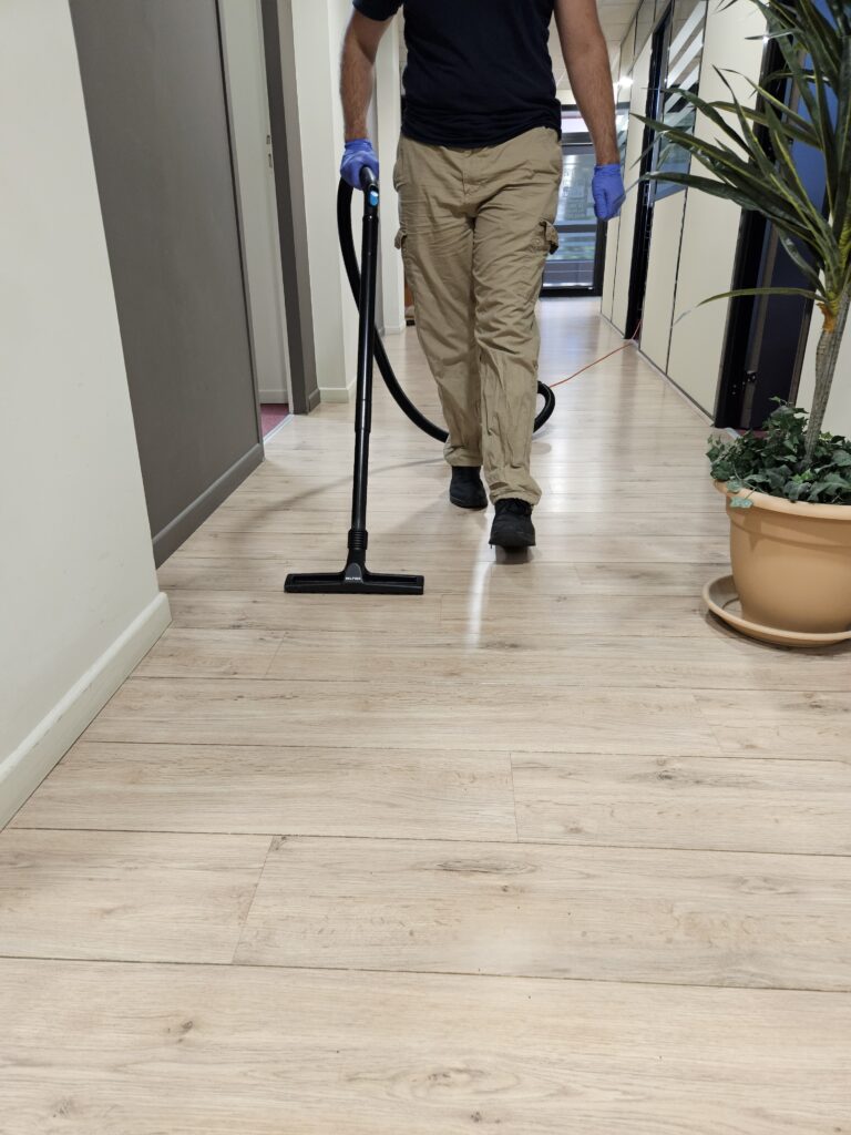 Étienne passe l’aspirateur sur le sol d’un couloir à domicile