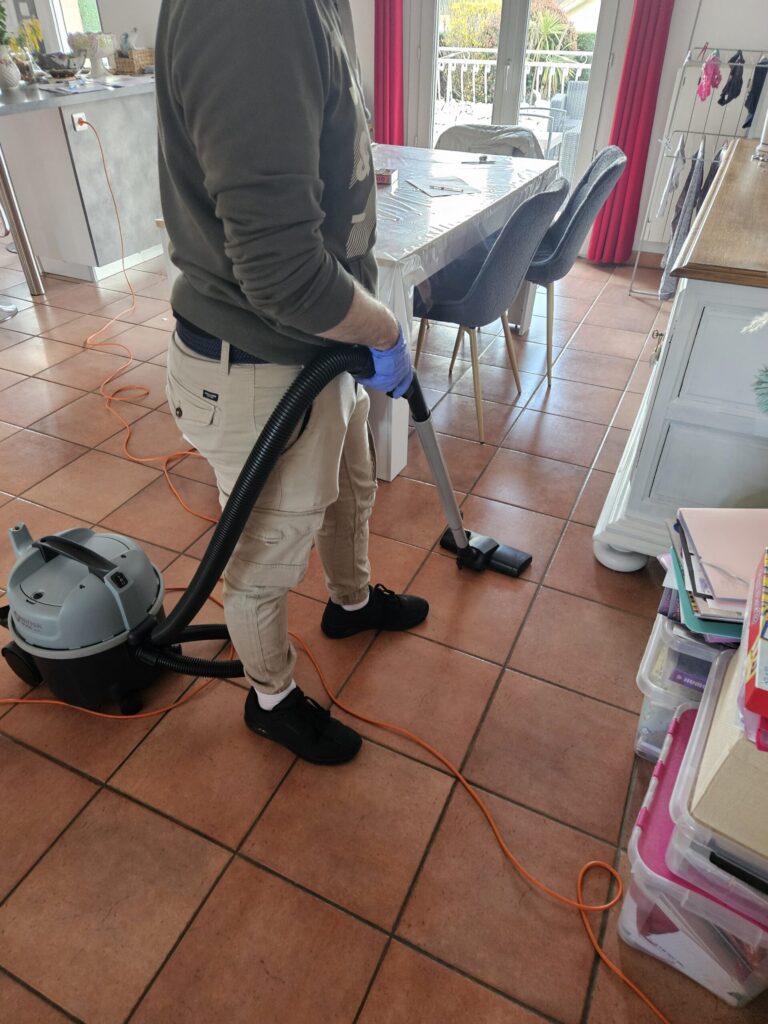 Étienne passe l’aspirateur sur le sol carrelé d’un logement